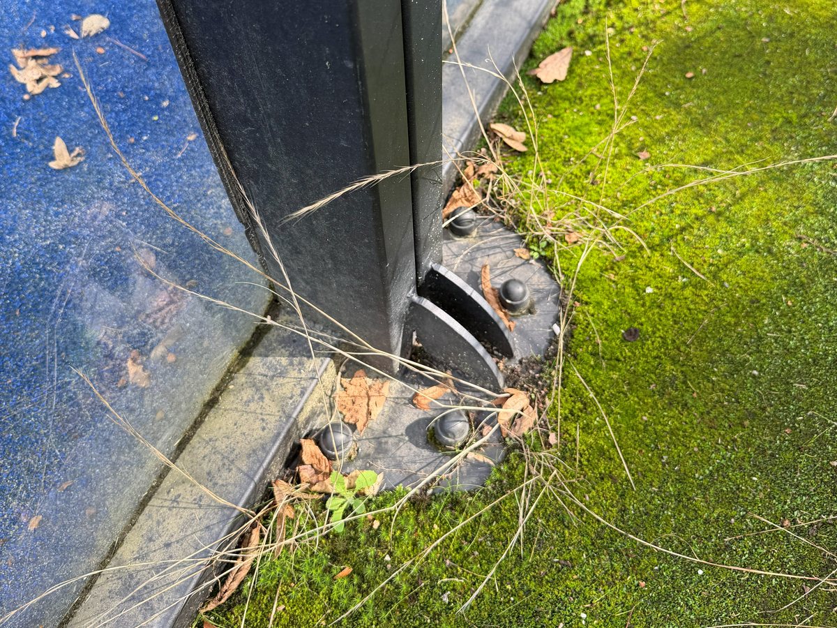 Algaanslag, zand en bladeren op de coating bij de onderrand van de kooiconstructie