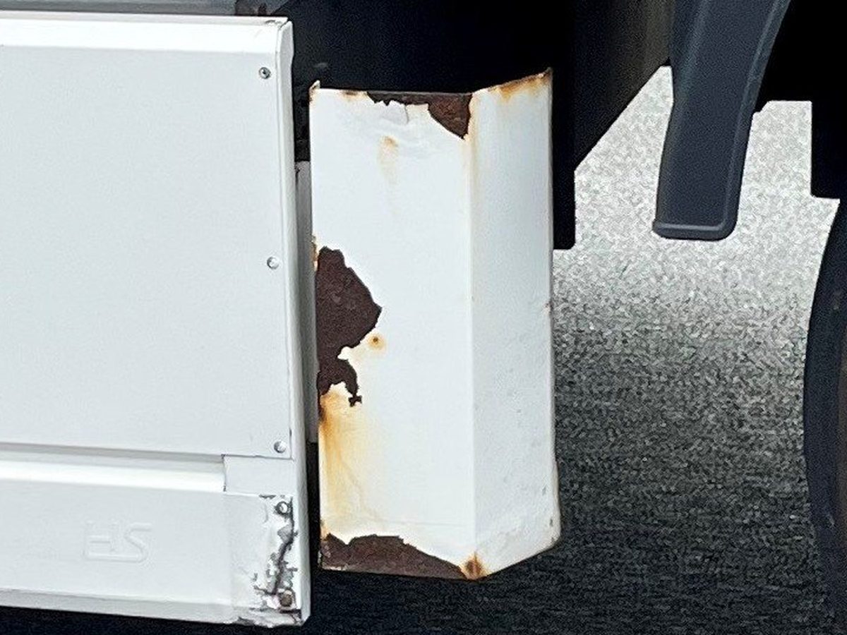 Steun achter de palletkist met afbladderende coating en rode roest die vanuit de randen begint
