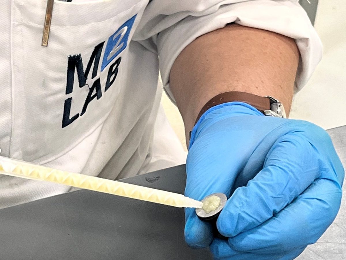 Laborant in M2LAB-labjas brengt met een spatel lijm aan op een dolly