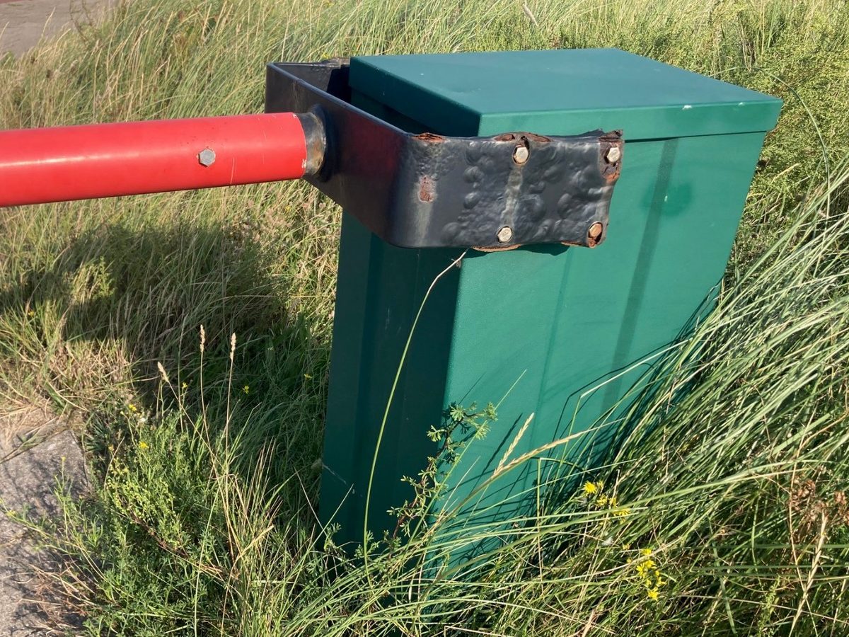 Groene behuizing en rode slagboom in goede staat, met de zwarte beugel ertussen