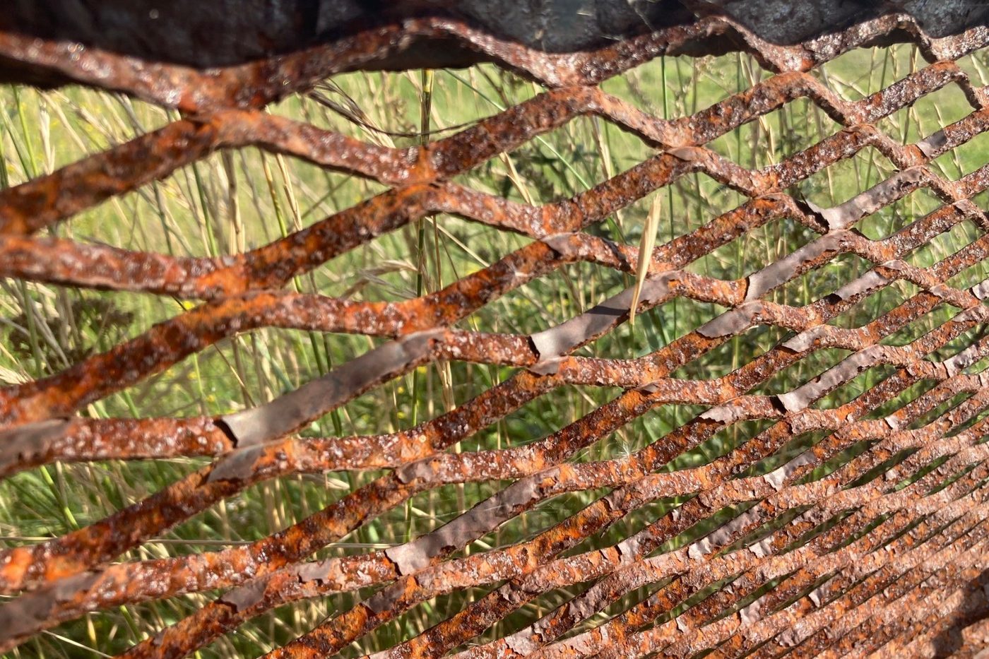 Close-up van verroest strekmetaal waarvan de coating in schilfers loslaat