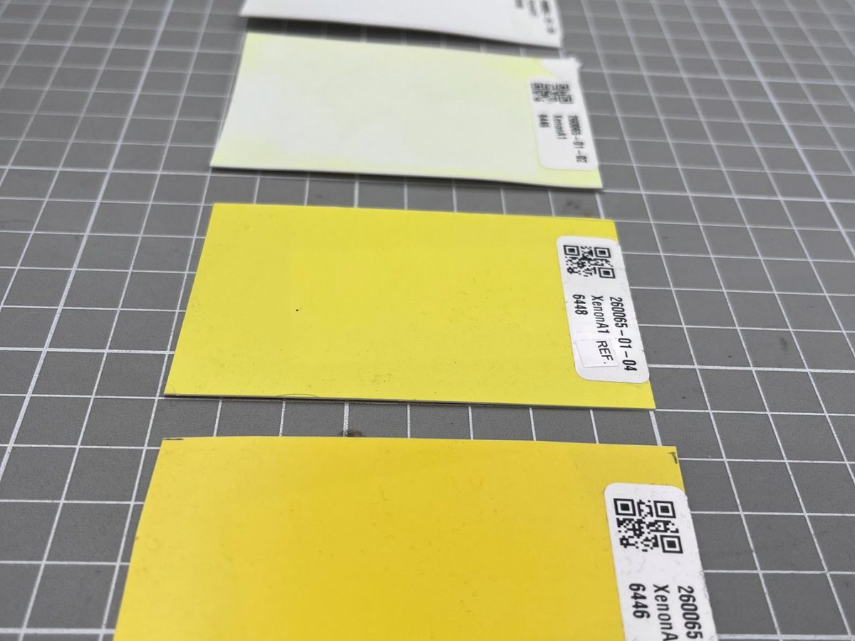 Gele testpanelen met QR-label na een verweringstest, van nog geel tot sterk verbleekt