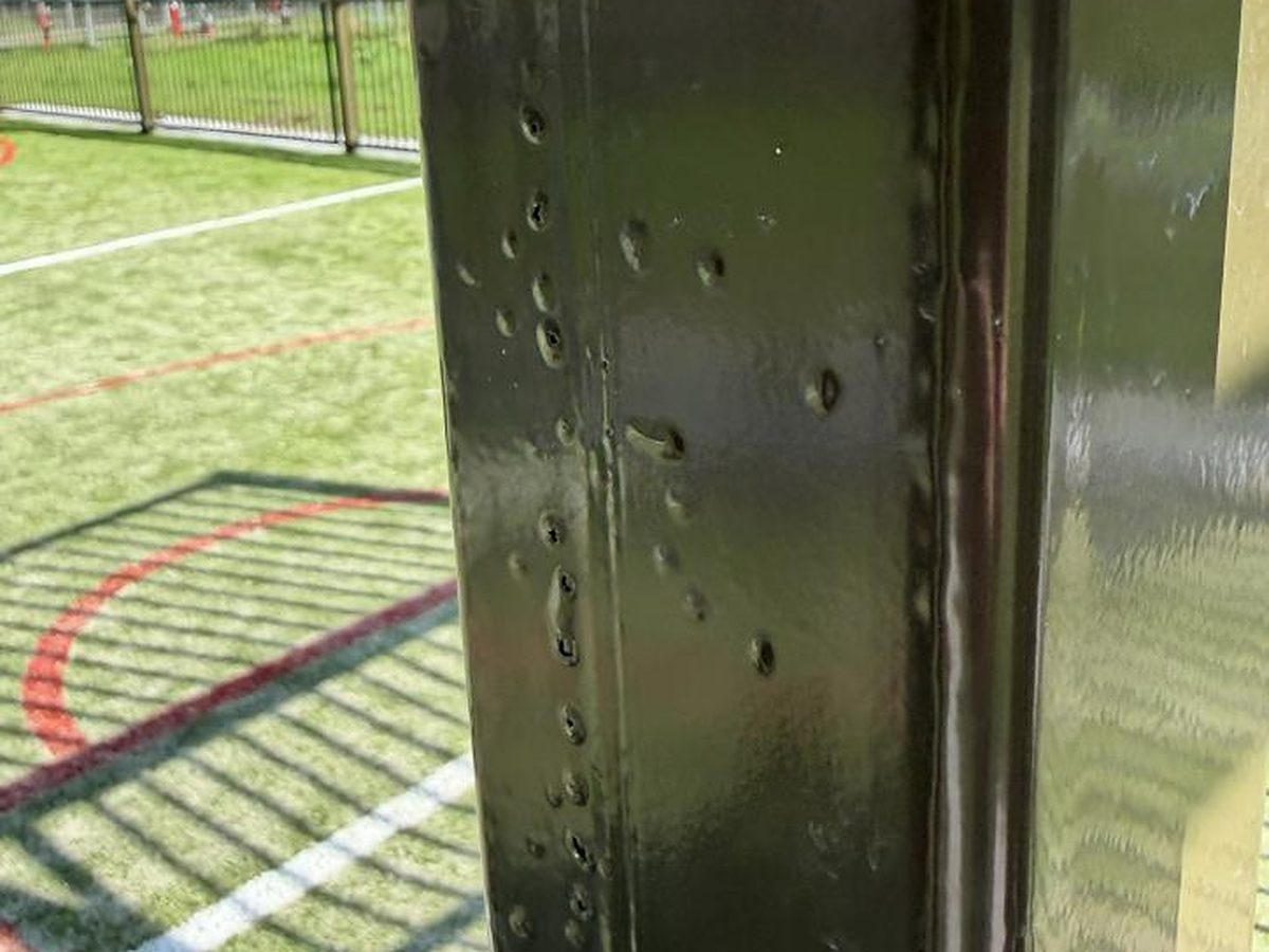 Dikke zinkspetters waar overheen is gecoat op een stalen koker van het voetbalcourt
